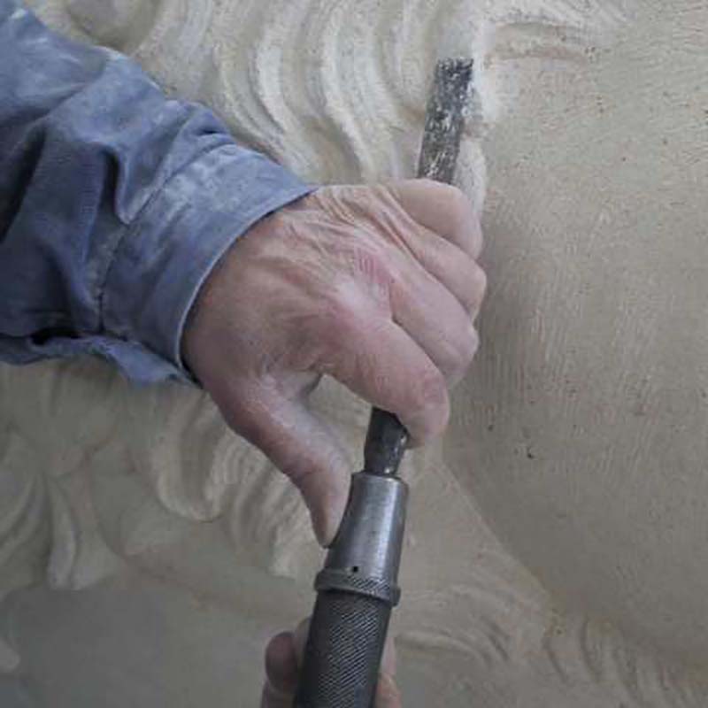 close up showing hand carving stone into a garden ornament